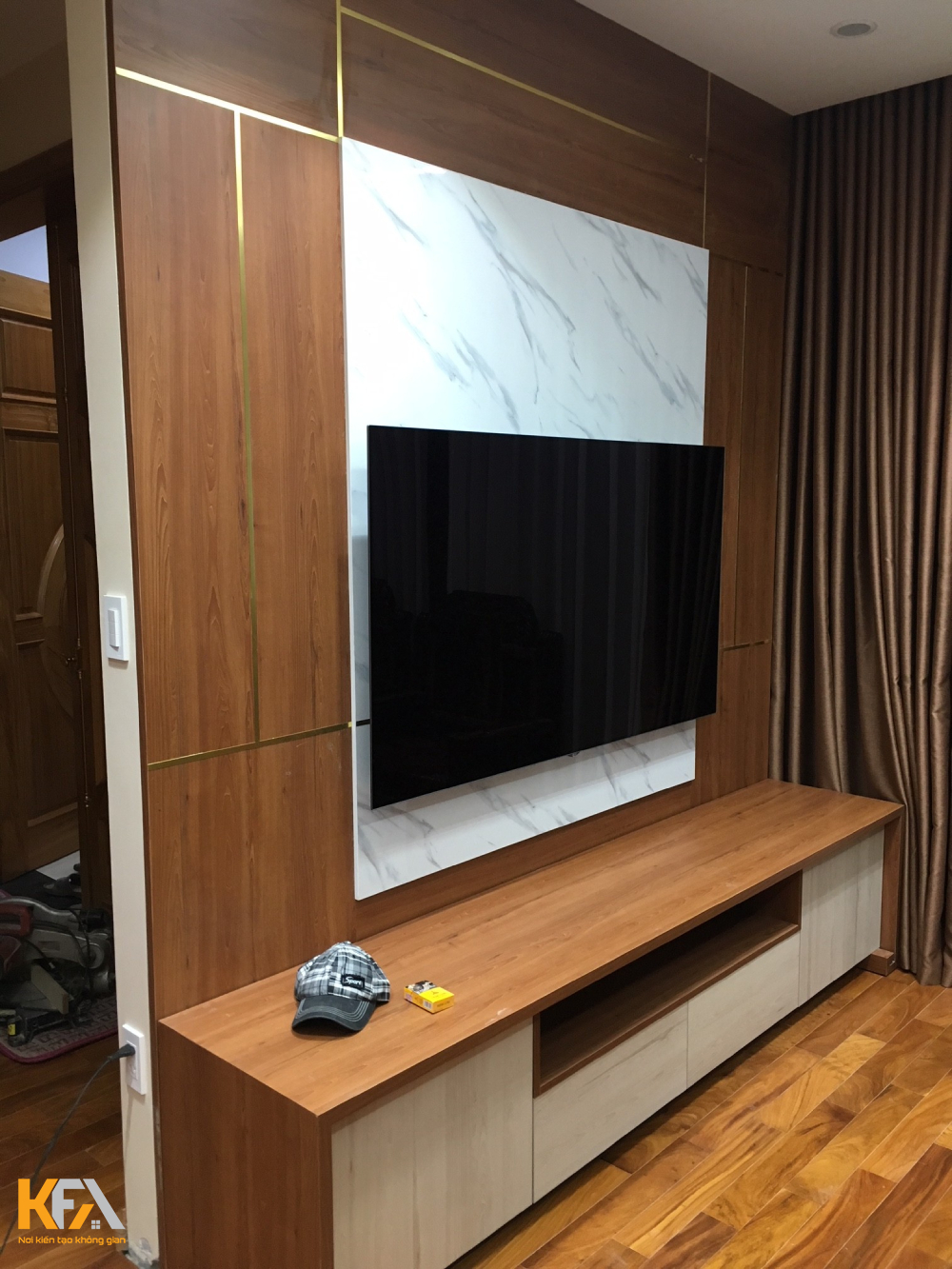 Toàn bộ nội thất gồm bàn ghế sofa, kệ tivi, vách ngăn trên tường đều bằng gỗ chống ẩm có phủ laminate